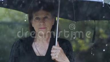 一个穿黑衣服<strong>的</strong>女人在雨中<strong>打伞</strong>